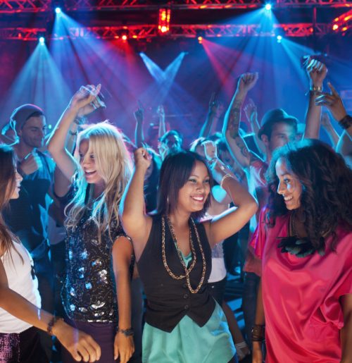 Smiling friends dancing on dance floor of nightclub